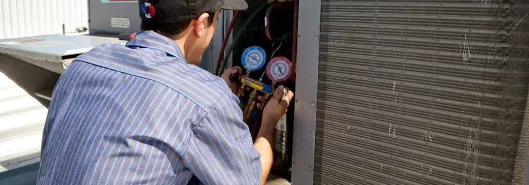 HVAC technician servicing a condenser unit in Mission Bend