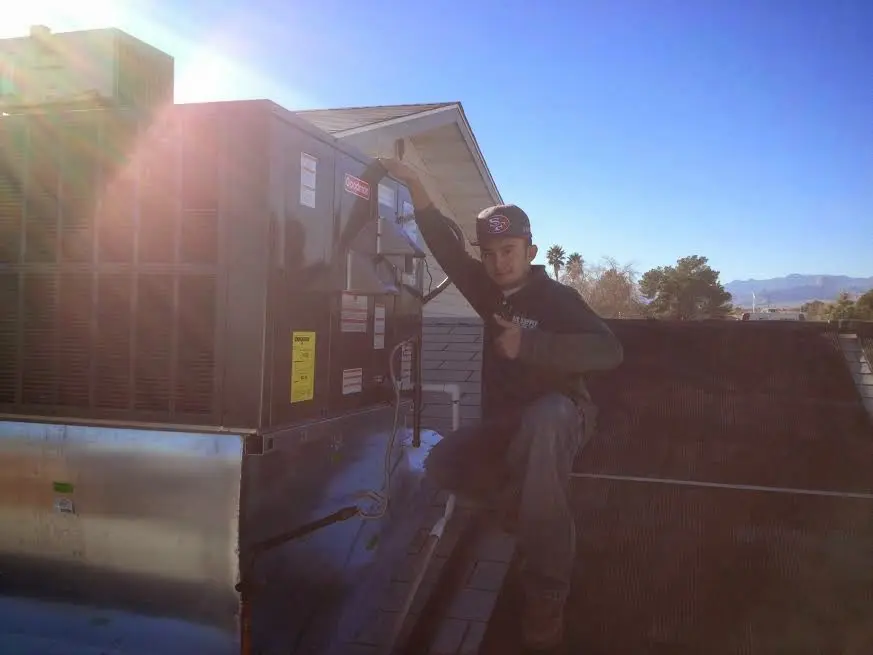 HVAC technician performing AC Tune-Up on a rooftop unit in Mission Bend